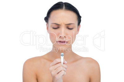 Uneasy brunette holding and looking at her nail clippers
