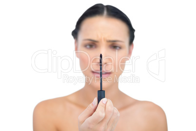 Annoyed young brunette looking at her mascara