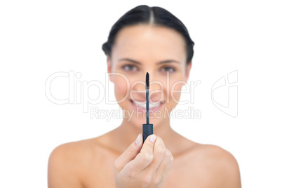Cheerful young brunette looking at her mascara