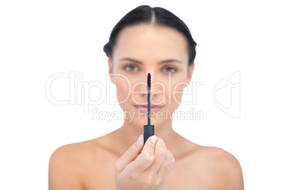 Serious young brunette holding mascara