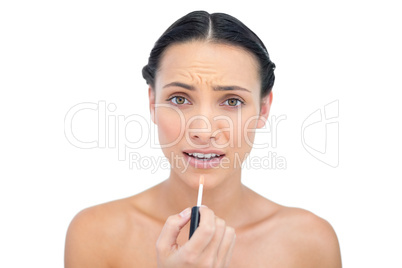 Young brunette applying lip gloss