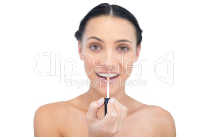 Smiling young model holding lip gloss while looking at camera
