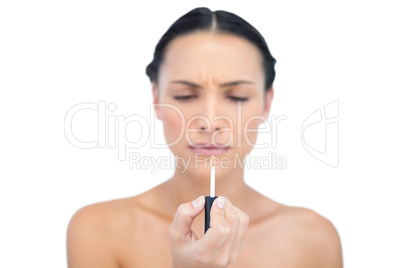 Serious young model holding natural lip gloss
