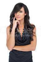 Pensive elegant dark haired model posing with finger on her chee