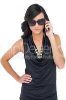 Serious elegant brunette wearing sunglasses on the phone