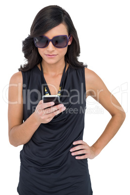 Concentrated elegant brunette wearing sunglasses texting
