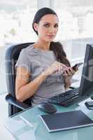 Serious businesswoman using calculator and looking at camera