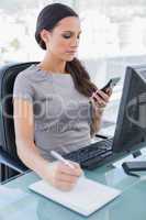 Businesswoman using calculator and writing