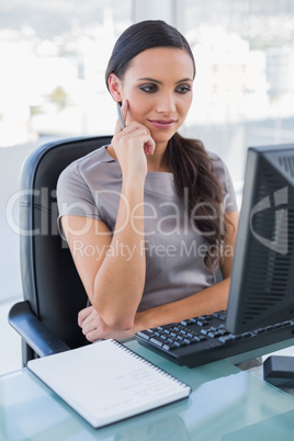 Thoughtful gorgeous businesswoman looking at her computer screen