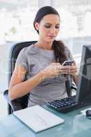 Concentrated gorgeous businesswoman texting on her smartphone
