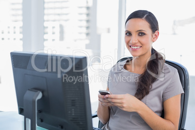 Happy dark haired businesswoman holding phone