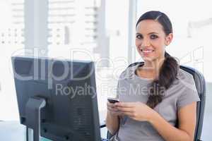Happy dark haired businesswoman holding phone