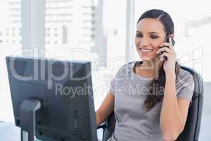 Smiling dark haired businesswoman having a phone conversation