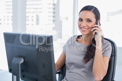 Cheerful dark haired businesswoman having a phone conversation