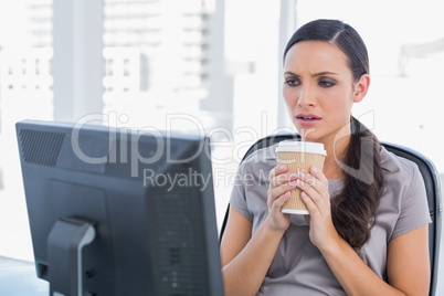 Unsmiling attractive businesswoman holding coffee