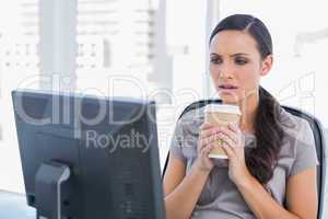 Unsmiling attractive businesswoman holding coffee