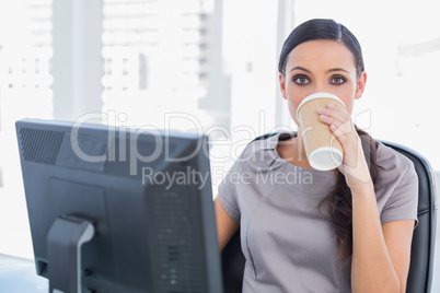 Attractive businesswoman drinking coffee and looking at camera