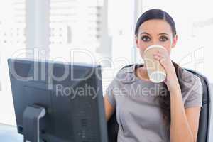 Attractive businesswoman drinking coffee and looking at camera