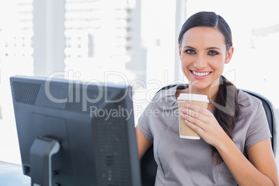 Attractive businesswoman drinking coffee and cheering at camera