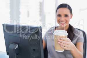 Attractive businesswoman offering coffee to camera