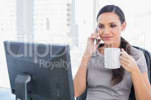 Attractive businesswoman holding coffee and answering phone