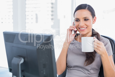 Cheerful attractive businesswoman holding coffee and answering p