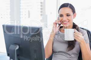 Cheerful attractive businesswoman holding coffee and answering p