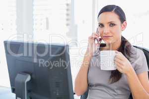 Relaxed businesswoman holding her coffee and phone