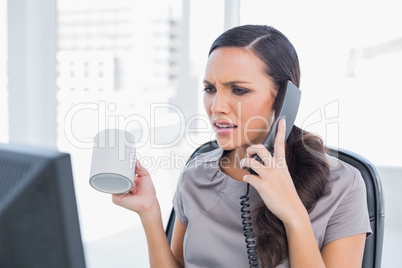 Irritated secretary answering phone and looking at computer scre