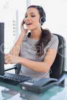 Attractive secretary wearing headset and pointing at computer sc
