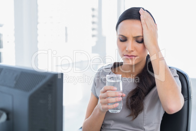 Attractive secretary with headache holding water and touching he