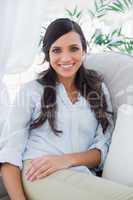 Smiling gorgeous brunette sitting on the couch