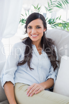 Cheerful gorgeous brunette sitting on the couch