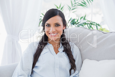 Happy gorgeous brunette sitting on the couch