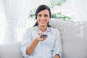 Smiling attractive brunette holding remote
