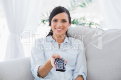 Cheerful attractive brunette changing tv channels