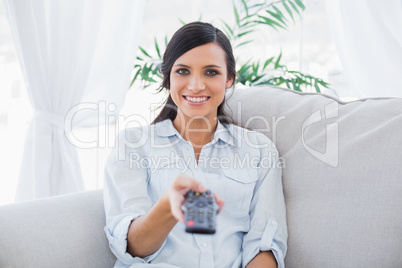 Smiling attractive brunette changing tv channels
