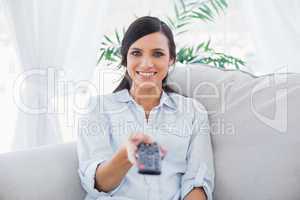 Smiling attractive brunette changing tv channels