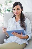 Attractive brunette holding tablet pc and credit card