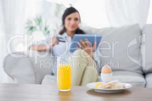Peaceful brunette having breakfast while buying online