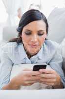 Dark hair woman lying on the couch sending messages
