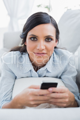 Relaxed dark hair woman lying on the couch sending messages