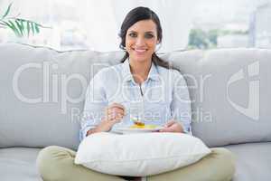 Woman sitting on the couch crossing legs eating fruits