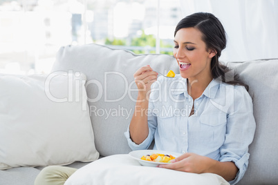 Woman relaxing on the sofa eating fruit salad