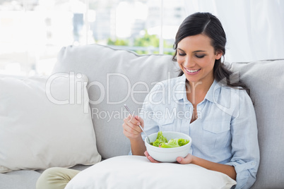 Woman relaxing on the sofa eating salad
