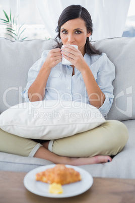 Cute woman drinking coffee and having croissant