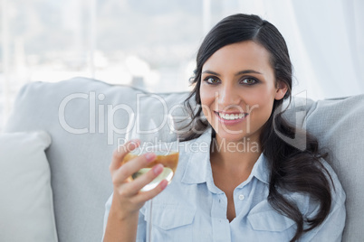 Seductive brunette drinking white wine on sofa