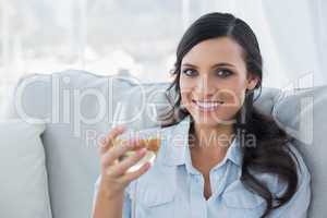 Seductive brunette drinking white wine on sofa