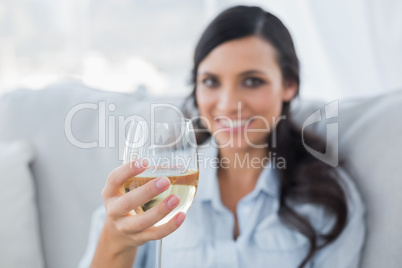 Seductive brunette offering white wine to camera