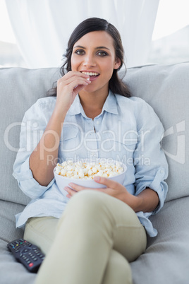 Pretty brunette watching tv with pop corn